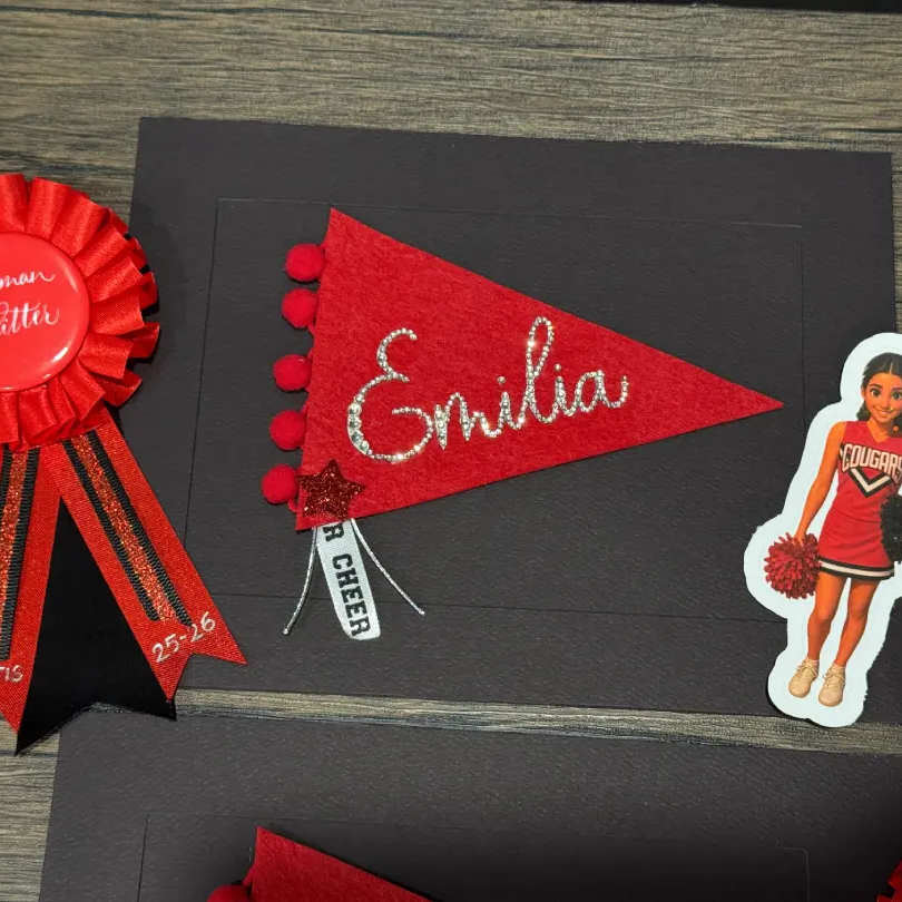 red pennant flag with bedazzled calligraphy name, cheerleader sticker and award ribbon